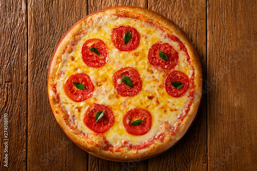 Pizza Margherita on wood background, top view. Pizza Margarita with Tomatoes, Basil and Mozzarella Cheese close up. Traditional Brazilian Pizza.