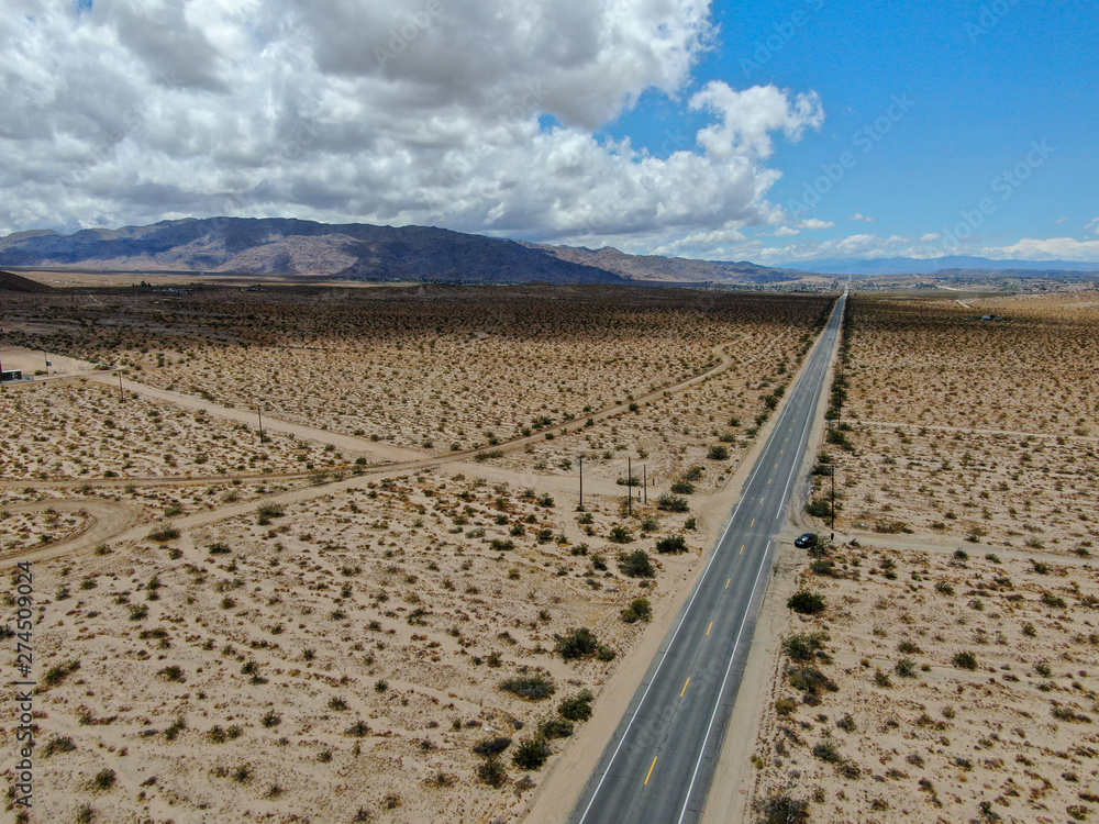 Aerial view of endless desert straight road next Joshua Tree Park. USA. Long straight tarmac road heading into the desert to the direction of Arizona.