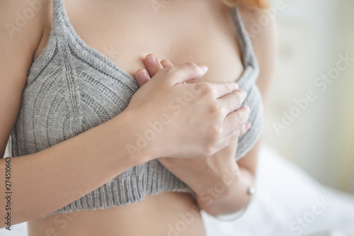 Young woman in grey  lingerie holding her breast because of having heart 