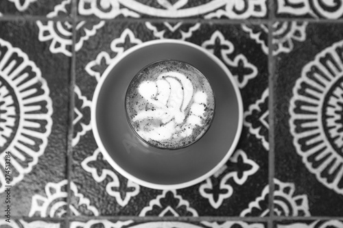 Charcoal latte on ornamental floor background. Trendy healthy organic drink.