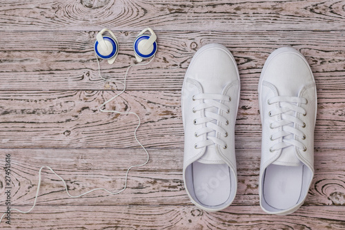 White sneakers and blue headphones on the wooden floor. Sports style. Flat lay.