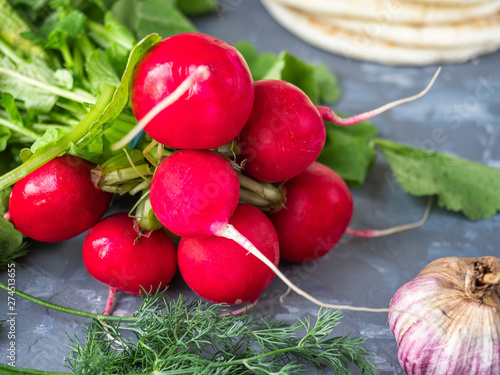 A bunch of fresh red radishes on a gray background shot from close range