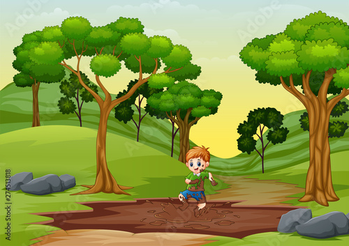 A young boy playing in a mud puddle