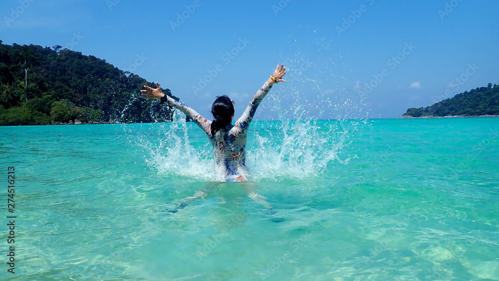 Beautiful young woman on the beach splashing water