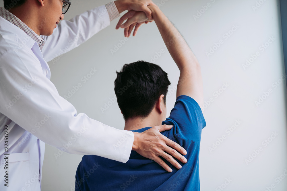 Obraz premium Chiropractor stretching a young man arm in medical office