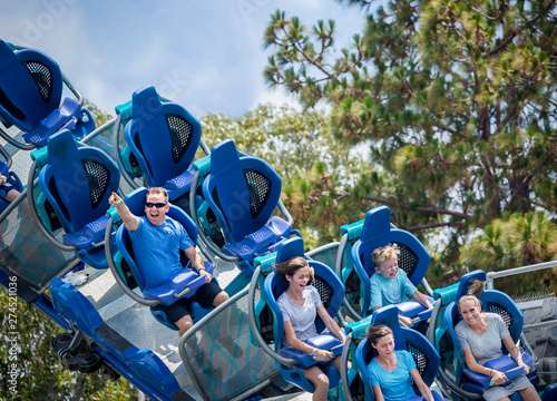 Vászonkép Young family having fun riding a rollercoaster at a theme park