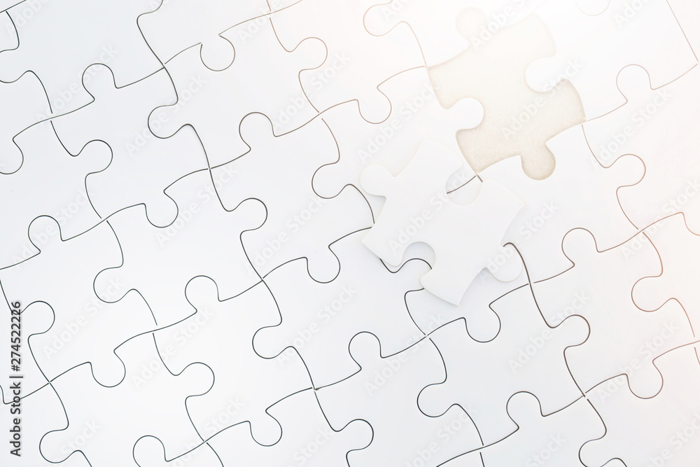 Close up Unfinished piece of white jigsaw puzzle. Complete the jigsaw puzzle with the missing pieces and Morning sunlight. concept of business challenge completion with teamwork. Close up Unfinished piece of white jigsaw puzzle. Complete the jigsaw puzzle with the missing pieces and Morning sunlight. concept of business challenge completion with teamwork.