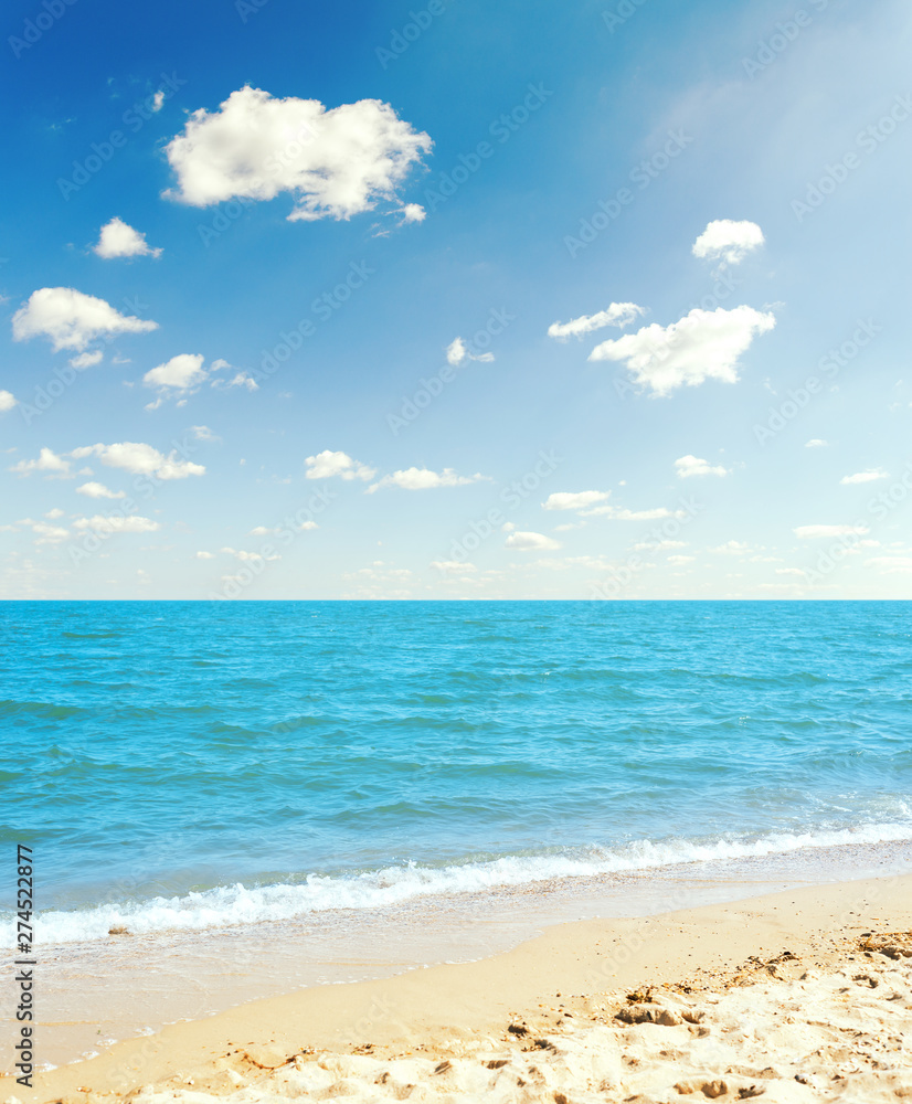 sea and yellow sand under blue sky with clouds