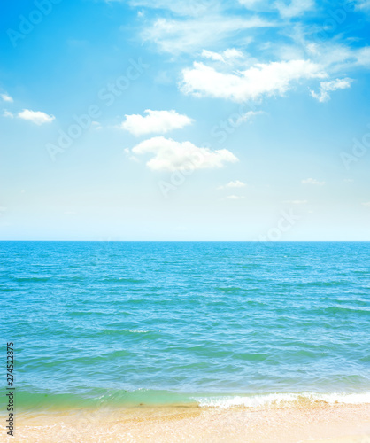 blue sky with clouds and sea with yellow sand