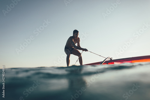 Young man uplift windsurf board sail