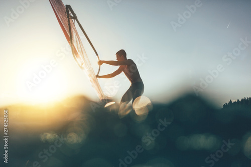 Low angle splashing view of windsurfer sailing on windsurf board photo
