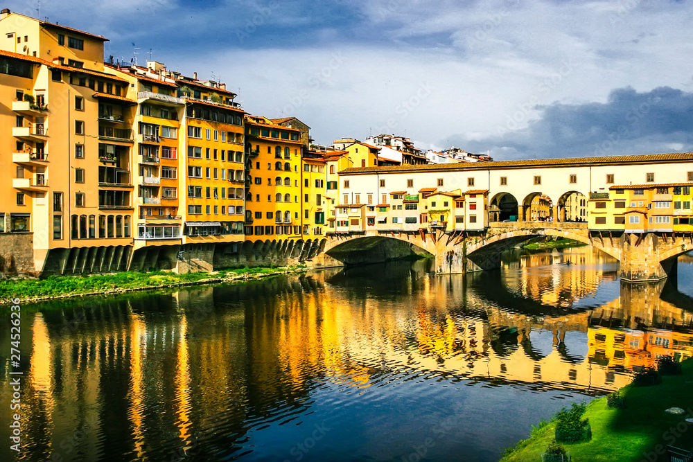 Obraz premium Old bridge Ponte Vecchio with colourful buildings houses and its reflection in the river Arno in Florance, Tuscany, Italy. April 2012