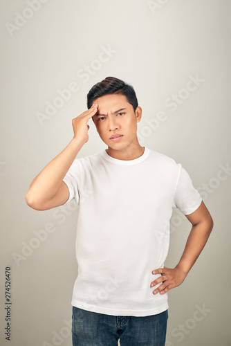 Good-looking asian man showing how much his head hurts, experiencing pain, looking miserable and exhausted