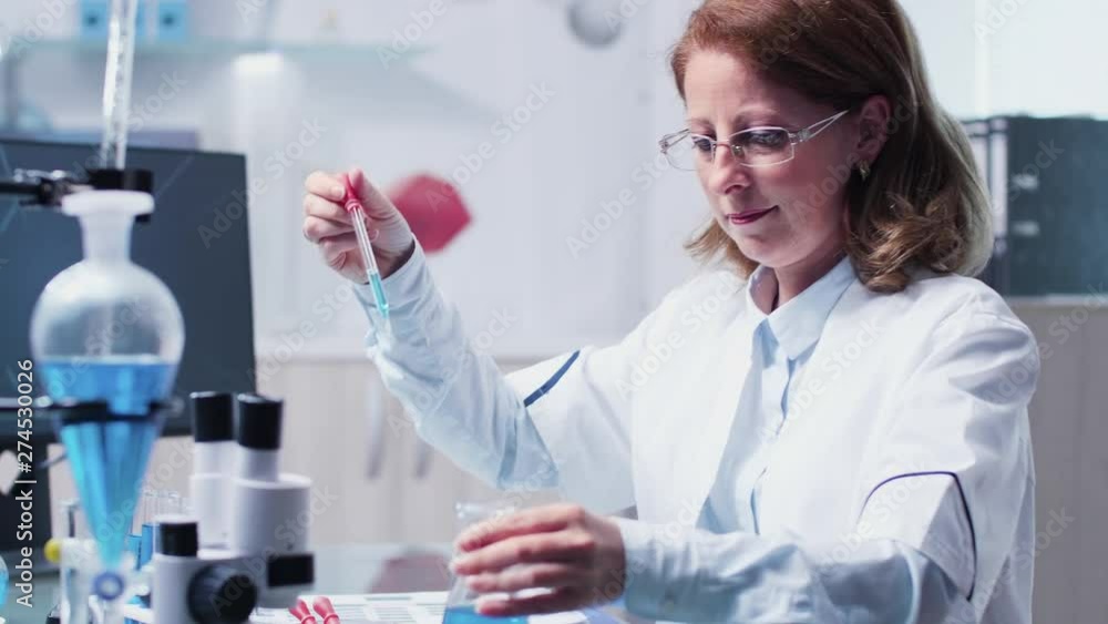 Female researcher takes samples from a tube. In the background - modern laboratory Female researcher takes samples from a tube. In the background - modern laboratory