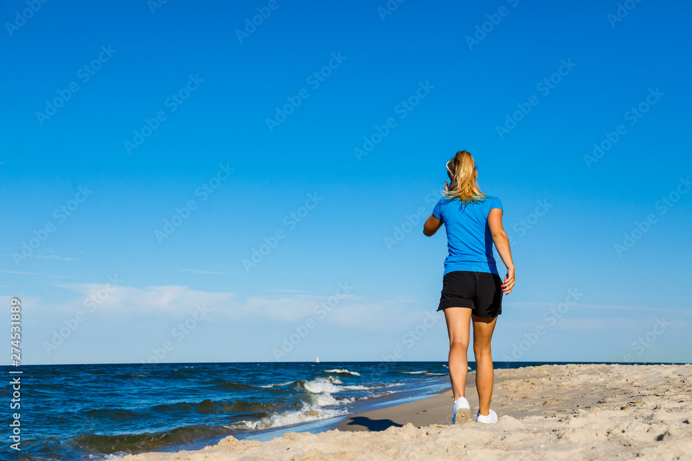 Young woman running, jumping on beach