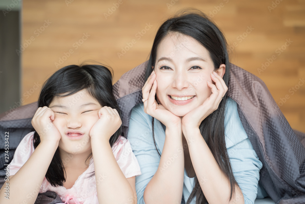 Mother and her daughter child girl playing in the bedroom and putting blanket on . Happy Asian family