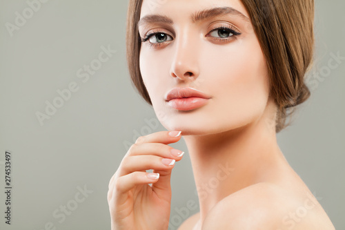 Beautiful face closeup. Pretty woman with perfect skin and french nails manicure