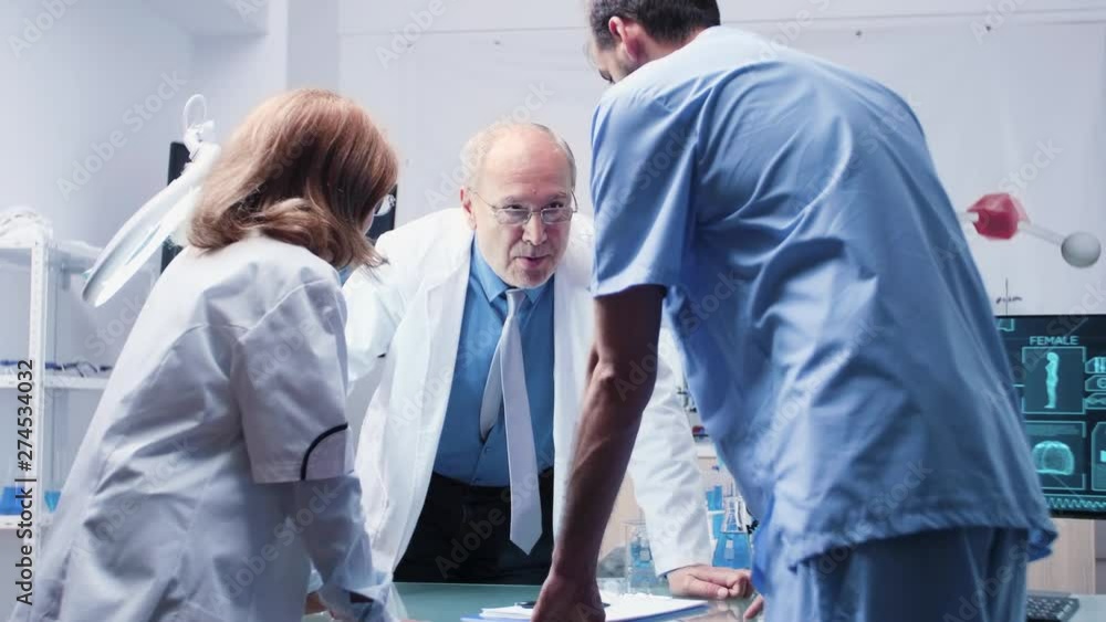 Team of scientists and an assistant are talking in modern high end laboratory Team of scientists and an assistant are talking in modern high end laboratory