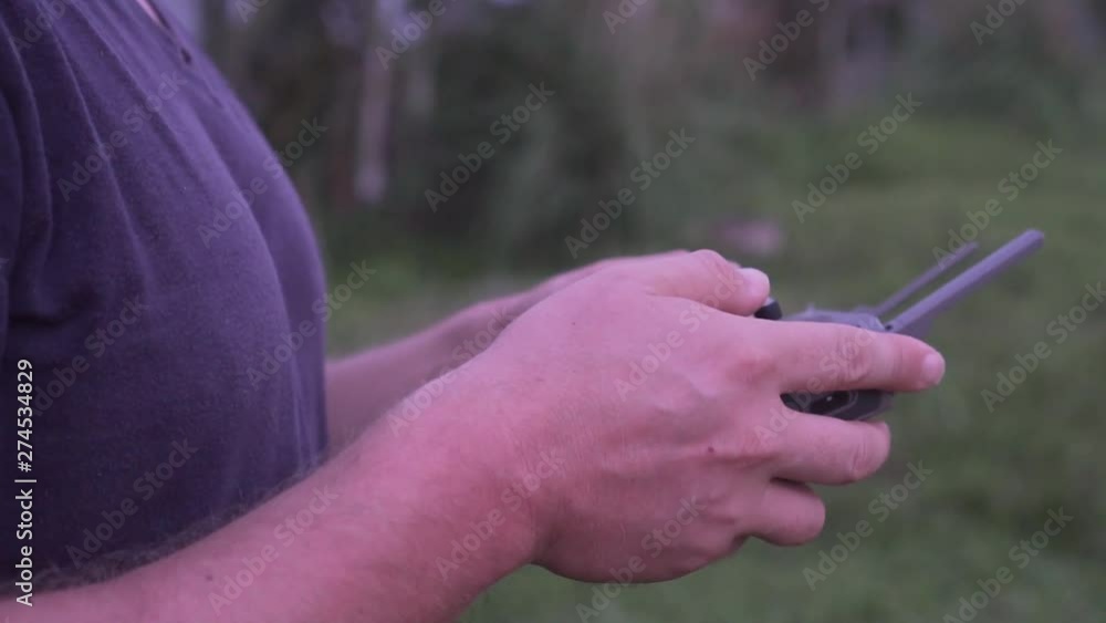 Man controlling drone outdoors. Closeup hands of drone operator holding remote control and smartphone Man controlling drone outdoors. Closeup hands of drone operator holding remote control and smartphone