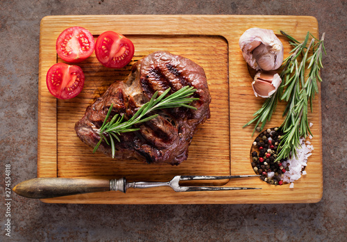 top view of grilled rib-eye steak with herbs and vegetables on wooden board