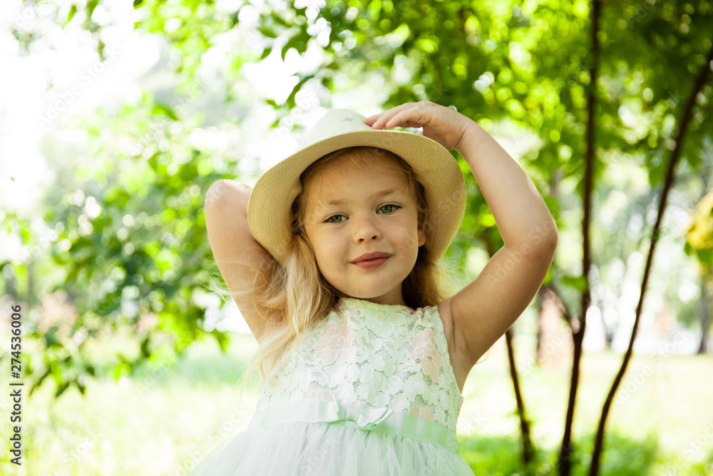 Portrait of cute child girl model in hat smiling in park or outdoor. Happy childhood, summer holidays and vacations. Portrait of cute child girl model in hat smiling in park or outdoor. Happy childhood, summer holidays and vacations.