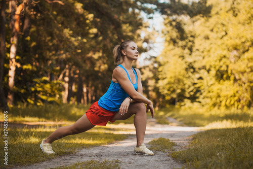 Pretty woman athlete doing exercises before jogging through the summer forest © Dmytro Titov
