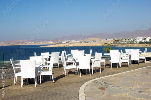 white tables on the terrace overlooking the sea