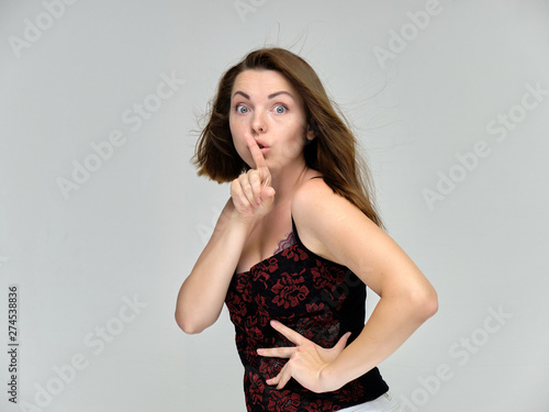 Closeup portrait of pretty girl, brunette woman 30 years old on a light gray background with beautiful dark hair and excellent skin of the face and body. She shows emotions, smiles, wonders. © Вячеслав Чичаев