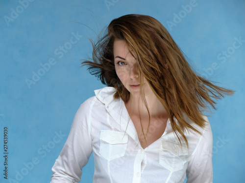 Wallpaper Mural A close-up portrait of a pretty girl, a brunette woman, 30 years old, against a blue background in a white shirt with dark hair and excellent skin. She shows emotions, smiles, wonders. Torontodigital.ca