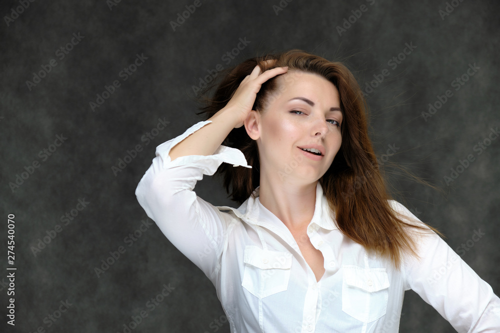 Closeup portrait of pretty girl, brunette woman 30 years old on a light gray background in a white shirt with dark hair and excellent skin. She shows emotions, smiles, wonders. Closeup portrait of pretty girl, brunette woman 30 years old on a light gray background in a white shirt with dark hair and excellent skin. She shows emotions, smiles, wonders.