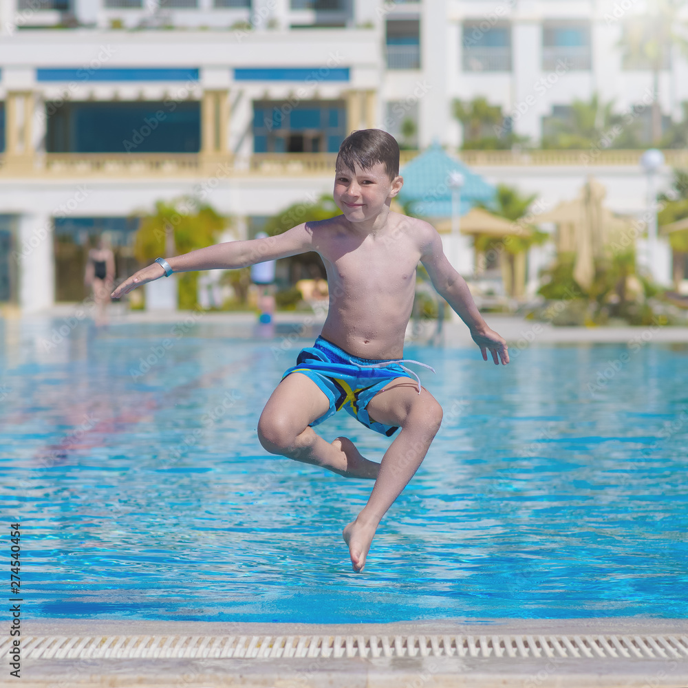 Caucasian boy making jump into swimming pool water.