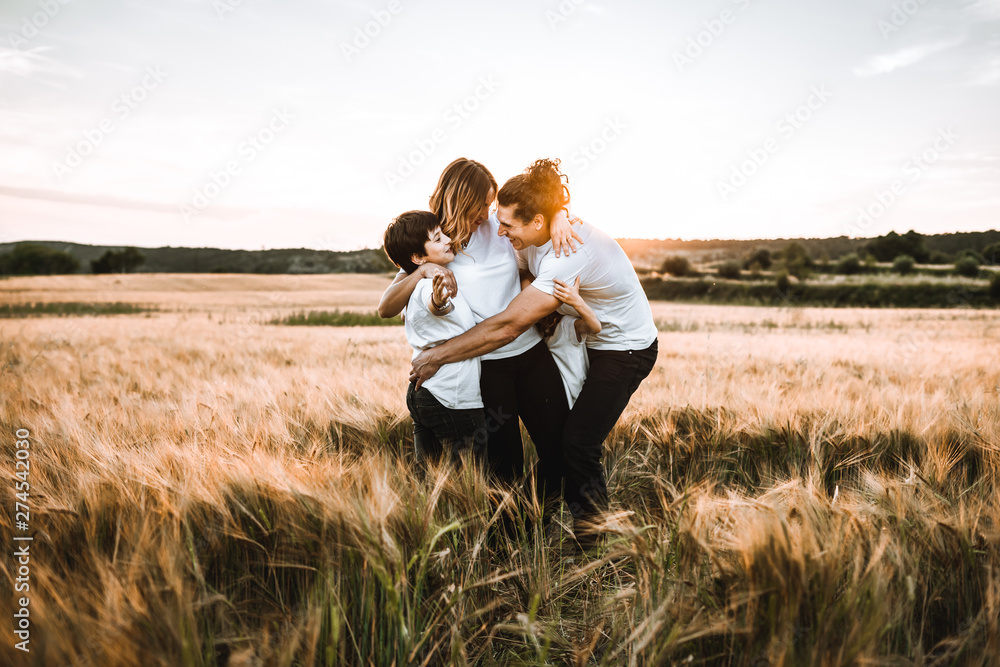 Happy family hugging in the field and smiling. Family in a sunset Happy family hugging in the field and smiling. Family in a sunset
