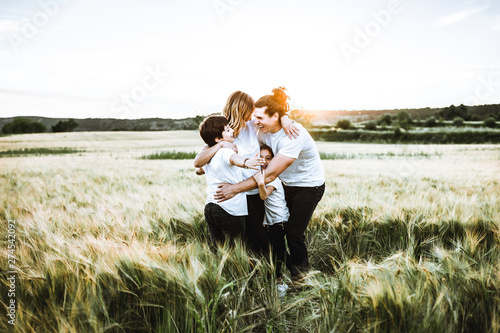 Happy family hugging in the field and smiling. Family in a sunset