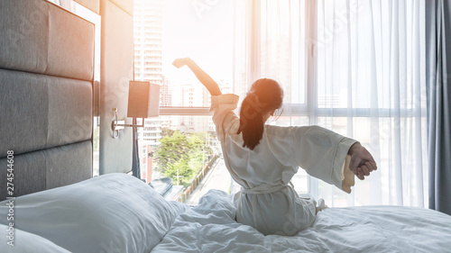 Hotel room comfort with good sleep easy relaxation lifestyle of Asian girl on bed have a nice day morning waking up, taking some rest, lazily relaxing in guest bedroom in city hotel photo