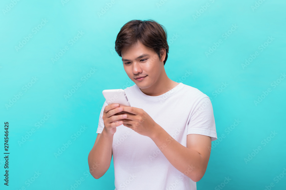 Young man texting message on smart phone isolated on blue background