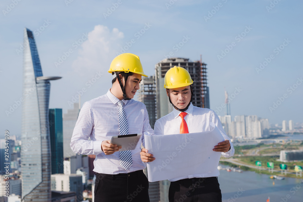 View of a Engineer and worker watching blueprint on construction site View of a Engineer and worker watching blueprint on construction site