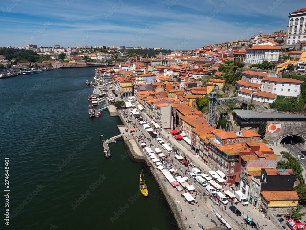 Porto, Portugal, may 2019: View over Porto old town with colorful buildings and red roofs. Promenadein Cais de Ribeira along Duoro river on a sunny day.