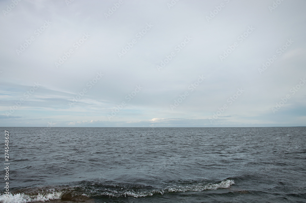 Grey sea water with horizon and greyish blue sky. Calm seascape