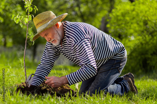 Photos Man wearing jeans and shirt standing on knees digging ground