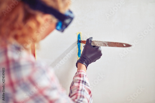 Working woman plastering / painting walls inside the house.