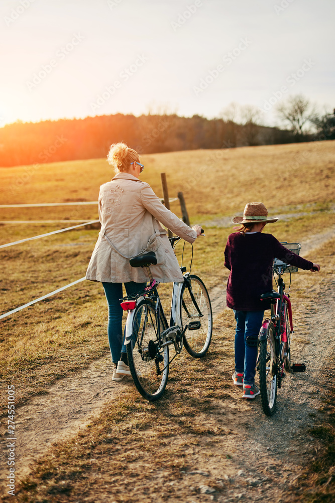 Obraz premium Mother and daughter with bicycles on countryside.