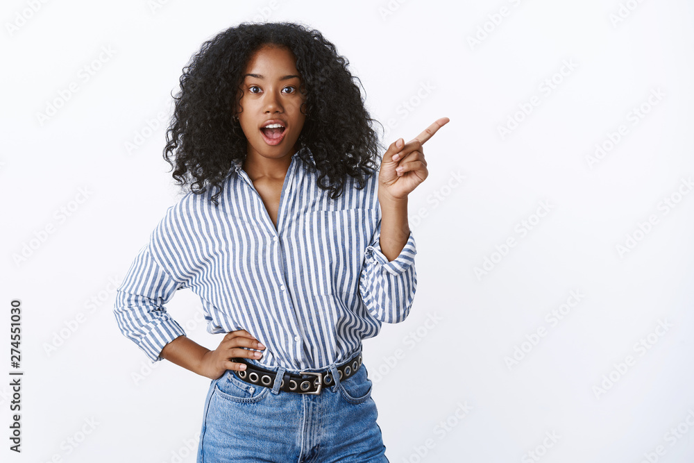 Astonished impressed woman asking friend what was that pointing sideways  questioned curious indicating side index finger open mouth intrigued  standing casually hand waist, wearing striped blouse Stock Photo | Adobe  Stock