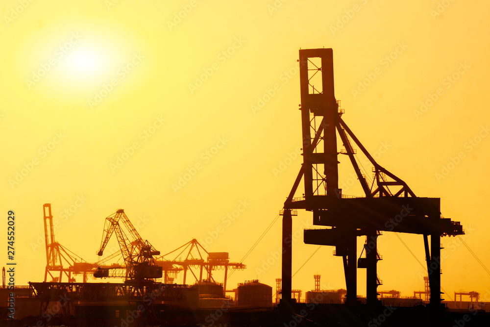 Closeup and Silhouette of container and gantry crane at Osaka port are loading on evening with sunset glow background. Closeup and Silhouette of container and gantry crane at Osaka port are loading on evening with sunset glow background.