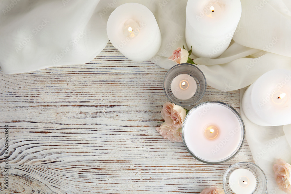 Flat lay composition with burning aromatic candles and roses on wooden table. Space for text - obrazy, fototapety, plakaty 