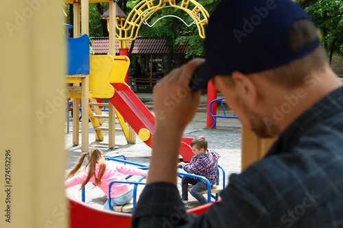 Obraz na plátně Suspicious adult man spying on kids at playground, space for text