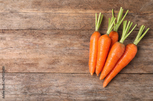 Carrots on wooden background, top view. Space for text
