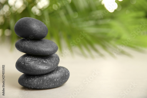 Stack of spa stones on table against blurred background. Space for text