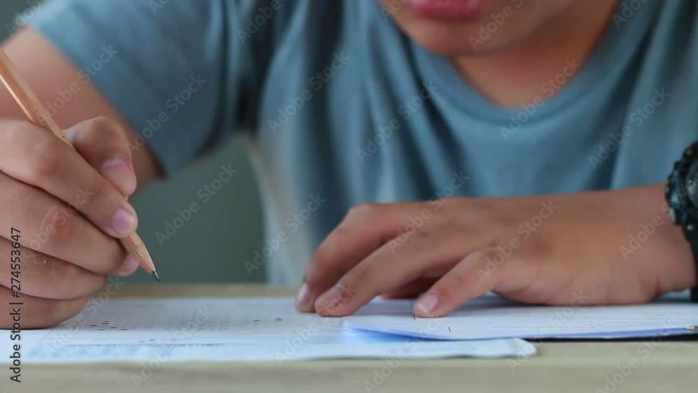 Education test in university or high school concept : Hands student holding pencil for testing exams on answer sheet, taking fill in exam document paper at campus classroom. Knowledge learning concept Education test in university or high school concept : Hands student holding pencil for testing exams on answer sheet, taking fill in exam document paper at campus classroom. Knowledge learning concept