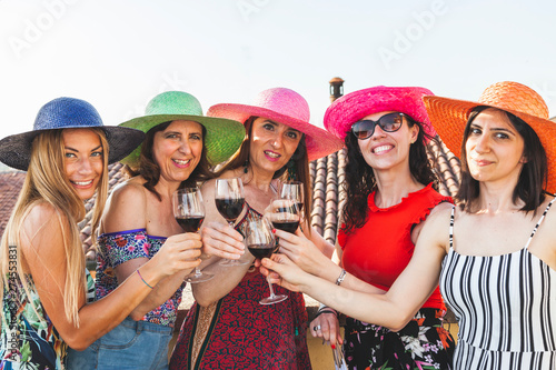 group of female friends wearing hats toasting red wine