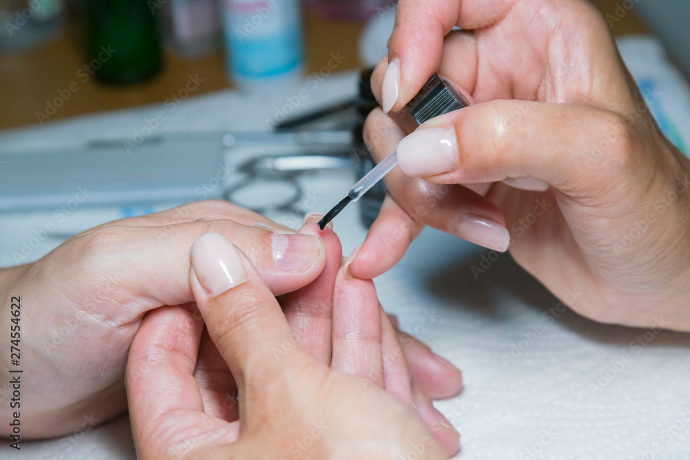 woman hand on manicure treatment with cuticle knife in beauty salon. applying a brush on acrylic nails in the salon woman hand on manicure treatment with cuticle knife in beauty salon. applying a brush on acrylic nails in the salon